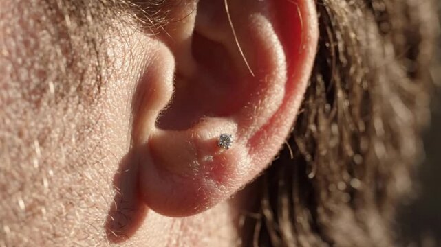 Closeup of a mans ear with a small diamond stud piercing