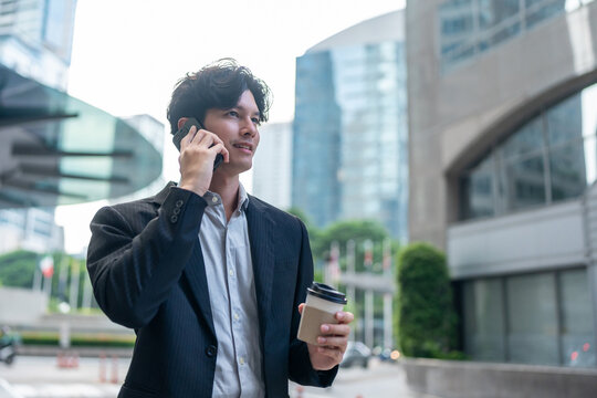Asian young businessman talking on mobile phone while spend time in city. 