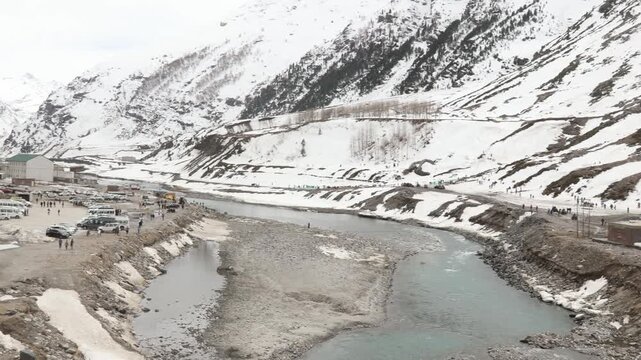Snow covered mountain landscape near Atal Tunnel in Manali Himachal Pradesh India. Scenic Himalayan winter view featuring frozen terrain, river stream and peaceful travel destination atmosphere.
