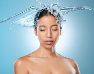 Naklejka premium Water, hair and splash with woman in studio for beauty, hydration cosmetics and cleaning. Self care, liquid and moisture with female person on blue background for shower, washing and shampoo