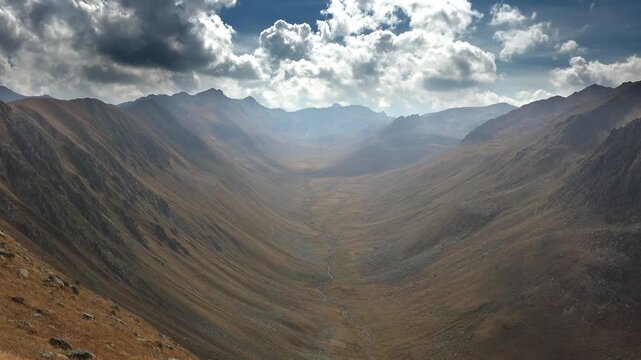 Timelapse Peru mountains and glacial U shaped valley under dramatic clouds in autumn. Fast motion captures andean ridgelines treeless moraine basin brooding sky fall colors.