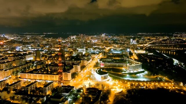 Ufa, Russia. TV tower and Salavat Yulaev Monument, aerial night panorama over the illuminated city center and Belaya River with golden streetlights reflecting on the water. Drone footage