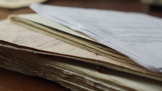 Close-up of aged papers falling onto a pile, evoking accumulation of evidence, archival research, or uncovering hidden historical records.