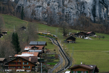 Scenic alpine village with traditional houses and green pastures set against dramatic mountains and rocky cliffs in a peaceful rural landscape. © Христя Сидор