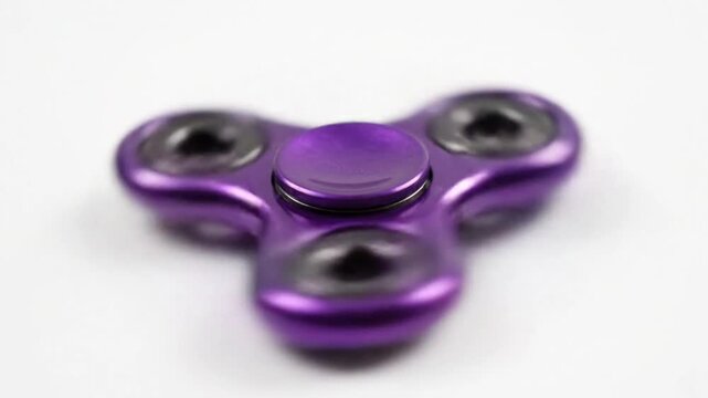 Close up view of a purple fidget spinner spinning and isolated on a white background