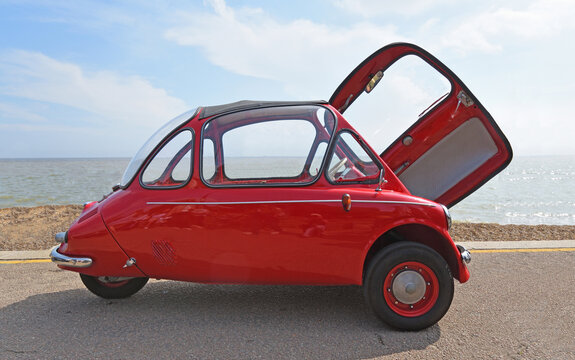 Classic red Heinkel Trojan 200 microcar or Bubble car parked on seafront promenade