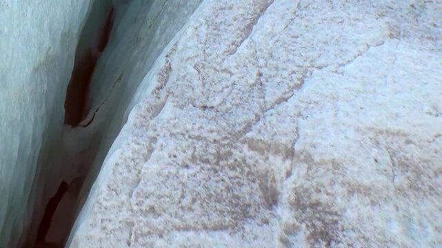Witness majestic meeting point of Arctic glacier and rugged earth. Icy blue and white surfaces reveal intricate textures and deep crevasses, signs of natural forces shaping this frozen wilderness.