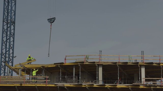 Laborers organize formwork and safety rails. Workers coordinate to install forms and safety barriers