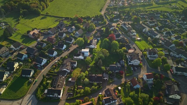 Aerial panorama of German countryside village with residential houses and green farmland at golden hour