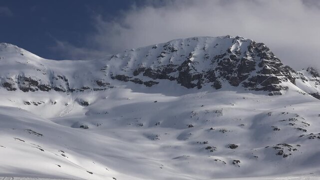 Timelapse winter mountains Pyrenees snowy peaks fast moving cold weather highland weather detail. Accelerated cloudbands sweep frozen ridges alpine corridor harsh climate light broad terrain texture.