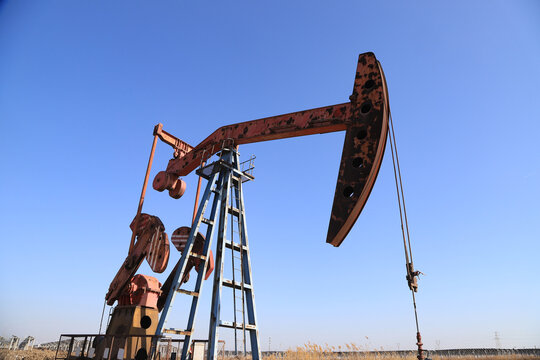 Rusted Red Oil Pump Jack Against Clear Blue Sky