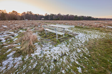 Naklejka premium Outdoor, landscape and nature in field with snow, sustainable environment and meadow bench. Grassland, winter season and wilderness with seat, conservation and countryside scenery of reservation
