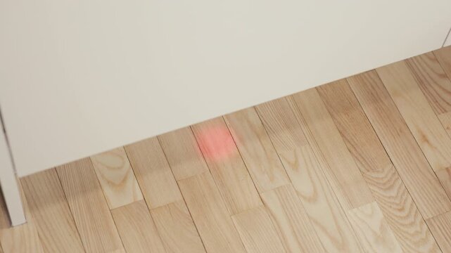 Dishwasher indicator: Careful alignment check of laser dot on wooden floor with warm ambient light