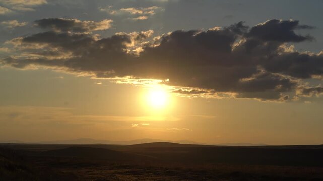Timelapse Gobi Desert sunset beneath partly cloudy sky arid dunes warm dusk glow. Rapid evening sequence crosses treeless wasteland amber light spreading across Mongolia.