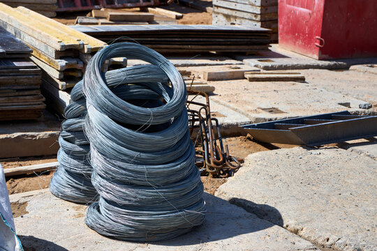Stacks of coiled steel binding wire on a busy construction site, essential for reinforcing structures and securing rebar foundations during building projects