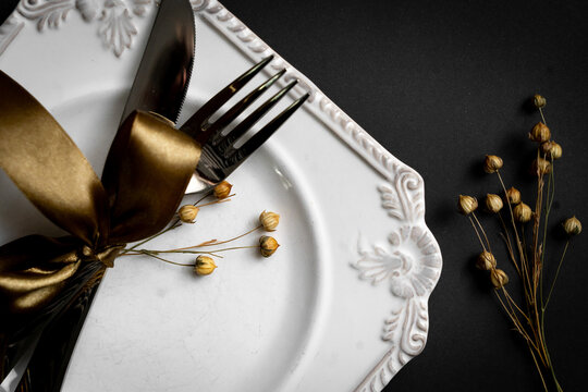 Romantic tabble setting with ribbon, plates, cutlery on black background. Empty plate. Mockup design layout for your text. Love romantic concept. Copy space. Top view. Flat lay.