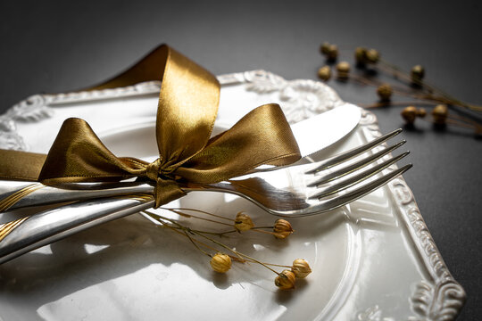 Romantic tabble setting with ribbon, plates, cutlery on black background. Empty plate. Mockup design layout for your text. Love romantic concept. Copy space. Top view. Flat lay.