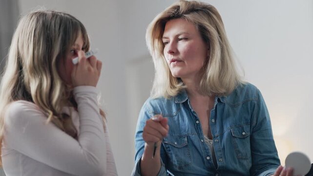 Mother and daughter applying makeup together at home