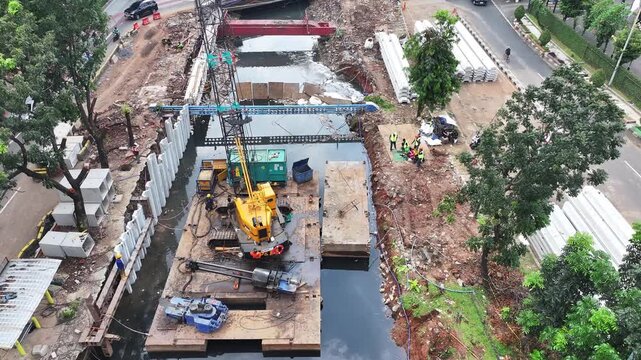 Sustainable Urban Planning for Future Cities Aerial view of bridge foundation construction on a river, featuring heavy steel sheet piling, concrete reinforcement, and a tall tower crane on a cofferdam