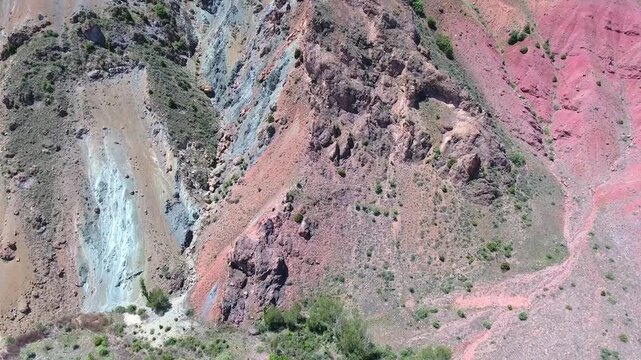 Exposed mineral outcrop reveals red strata and ore bearing layers across a barren slope. Mining geology and weathered bedrock create a survey scene with resource detail and rough terrain.
