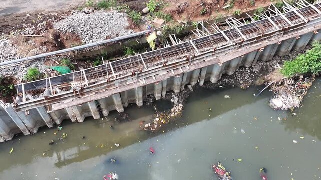 Sustainable Urban Planning for Future Cities Aerial view of bridge foundation construction on a river, featuring heavy steel sheet piling, concrete reinforcement, and a tall tower crane on a cofferdam