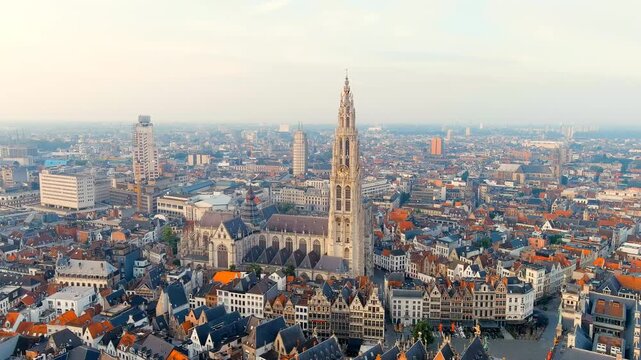 Antwerp, Belgium. The 123-meter Gothic spire of the Cathedral of Our Lady rising above the historic city center, aerial panoramic view over the Scheldt River at summer morning light. Drone footage, P