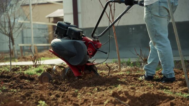 Man preparing garden soil with motor cultivator