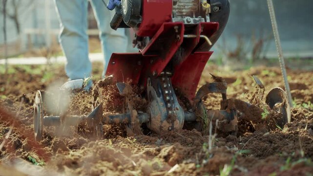 Closeup of motor cultivator plowing garden soil