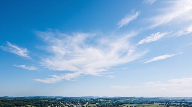 Vast blue sky with delicate wispy white clouds over rural land