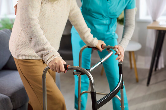 Nurse supports senior woman with walker in healthcare. Caregiver offers mobility assistance, promoting movement and confidence for rehabilitation and recovery. Clear concept of supportive care.
