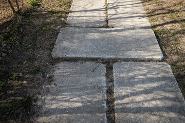 Fototapeta premium Damaged Concrete Sidewalk Slabs With Uneven Surface in Residential Area