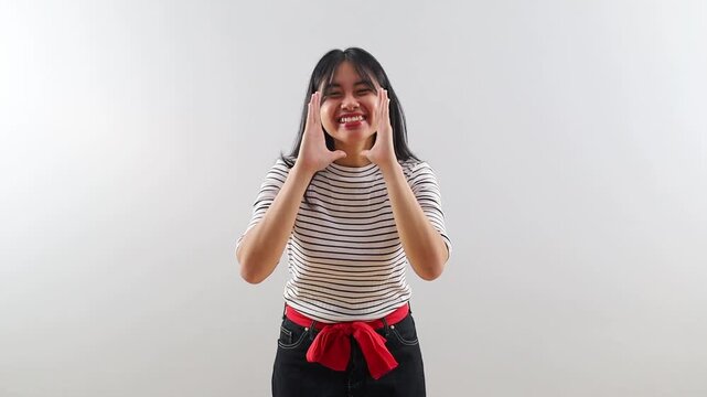 Friendly cheerful Asian woman shouting or calling out loudly with cupped hands