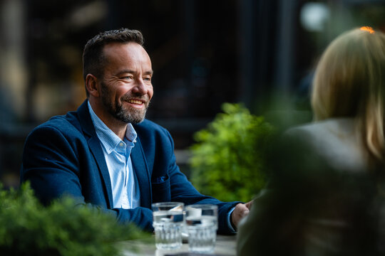 Smiling man having business conversation at outdoor cafe
