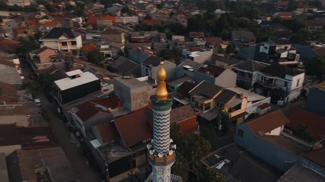 Aerial drone shot of mosque minaret with loudspeaker in residential area in Jakarta