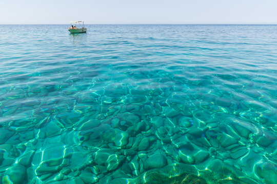 Clear turquoise blue water with speed boat on small Kastelli beach on Corfu island. High speed boat trip on Ionian sea. Natural seascape Corfu.