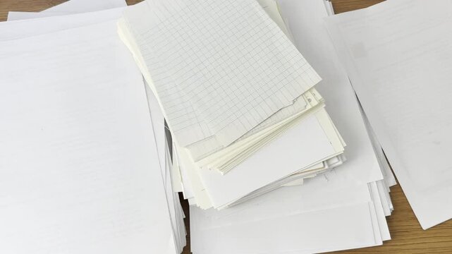 Video of scattered papers spread across a desk. Messy workspace scene representing stress, paperwork, office chaos, disorganization and busy work routine.