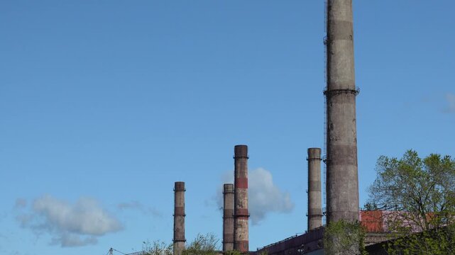 Upward camera movement showing smokestacks of inactive industrial factory without smoke emissions. 4K footage symbolizing shutdown industry, crisis and deindustrialization.