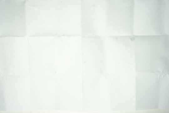 Texture of crumpled and folded white paper. Background of messy creased paper sheet with grid lines from folding, top view surface texture.