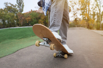 Fototapeta premium Legs of young man with skateboard in park, closeup