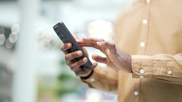 Close up of african american male hand using mobile phone smartphone standing in shopping center mall or supermarket. Black man use online app store for discount, sale promotions. light bokeh Closeup