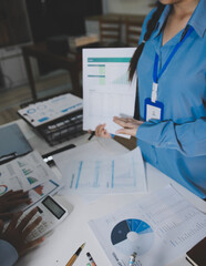 The businesswoman is using a white calculator to check company financial information, she is checking company financial information from the documents provided by the finance department.
