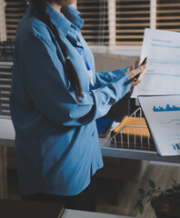 The businesswoman is using a white calculator to check company financial information, she is checking company financial information from the documents provided by the finance department.