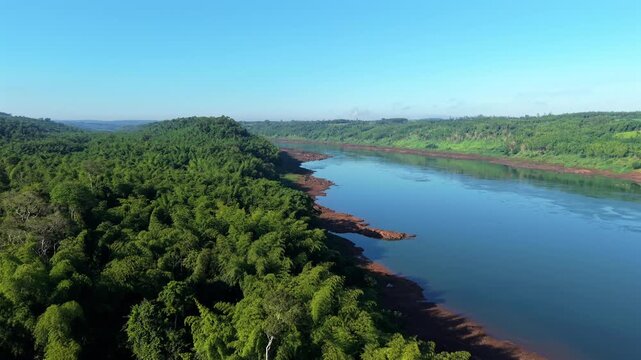 Paran&aacute; River in Misiones Argentina with broad water channel bordered by dense subtropical rainforest and irregular shoreline visible from elevated perspective smooth anticlockwise drone orbit aerial