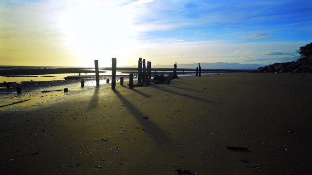 Marine Pier pilings sunrise Tasman Region Cape Farewell Collingwood South Island Time Lapse New Zealand timelapse low tide beach harbor view vertical post shallow water Waikato Beach clouds motion