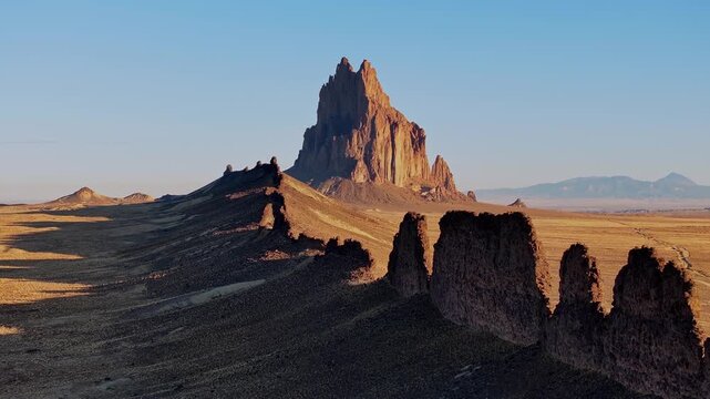 Smooth aerial movement past sharp desert ridges with Shiprock dominating the distant horizon