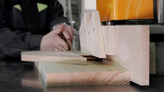 Close up of carpenter shaping wooden board on woodworking machine in furniture factory. Wood processing and furniture manufacturing concept.