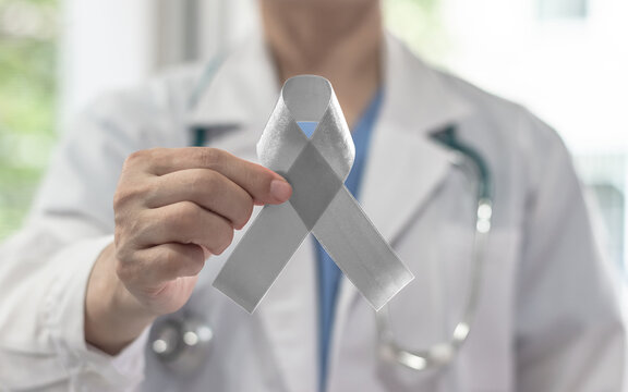 Silver color ribbon awareness on doctor's hand support, symbolic bow color for Parkinson's disease, Brain cancer, Schizophrenia, Sciatic Pain and Brain disorder or disability illness