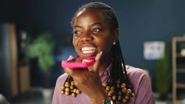 Young woman recording and sending voice message using smartphone at home office. Mobile communication and social media concept.