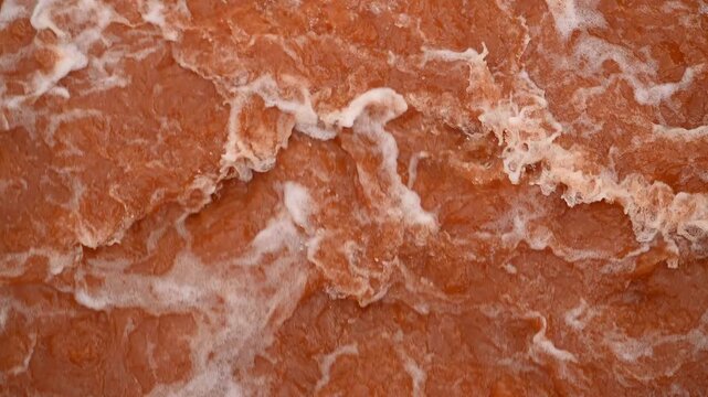 Abstract red water texture with foam patterns and swirling waves, natural background surface with copy space. Abstract orange-red texture from an iron and steel manufactory, molten metal or industrial