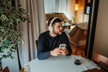 Man relaxing at home listening to music on smartphone © Dusan